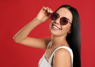 Photo of Beautiful woman wearing sunglasses on red background