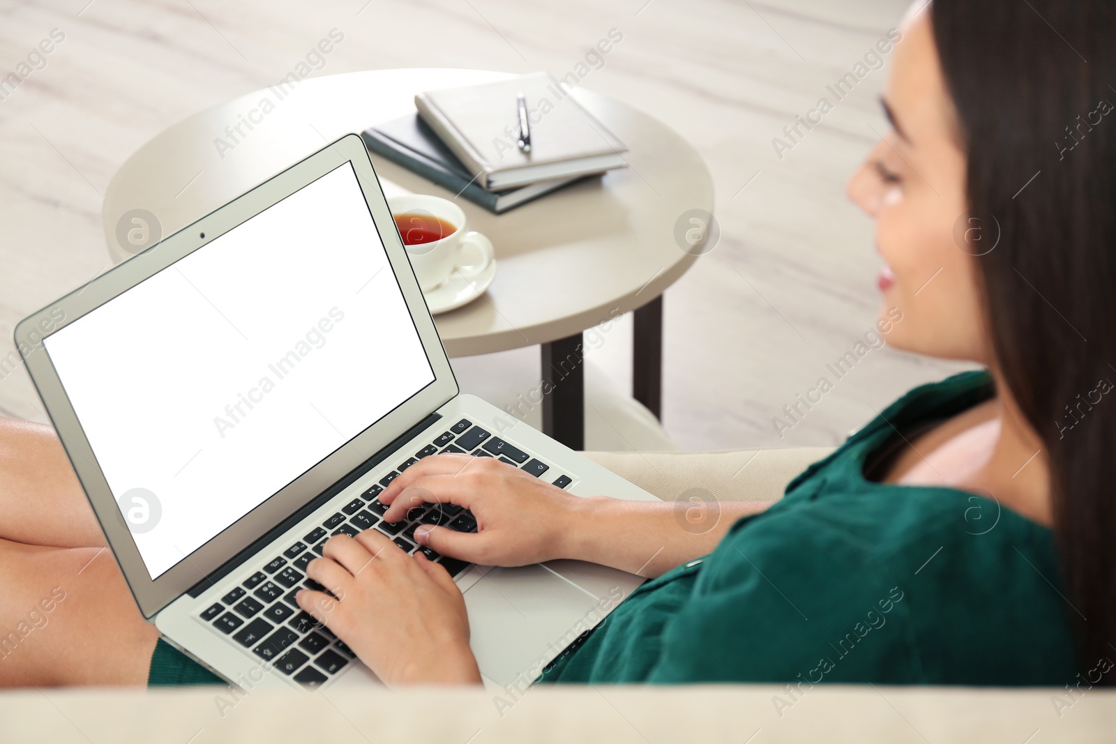 Photo of Young woman working on laptop in living room, focus on hands. Home office concept