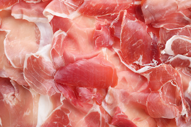 Tasty prosciutto slices as background, top view