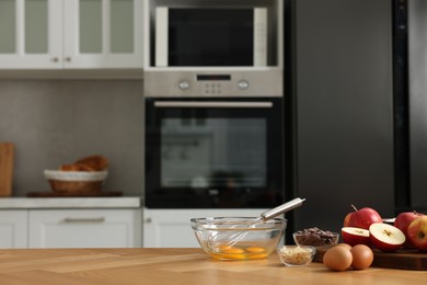 Cooking process. Metal whisk, bowl and products on wooden table in kitchen. Space for text