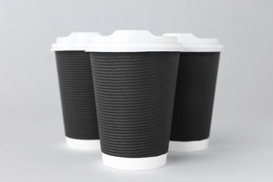 Paper cups with white lids on light grey background. Coffee to go