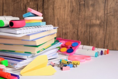 Photo of Many different books, paper plane and school stationery on white table, space for text. Back to school