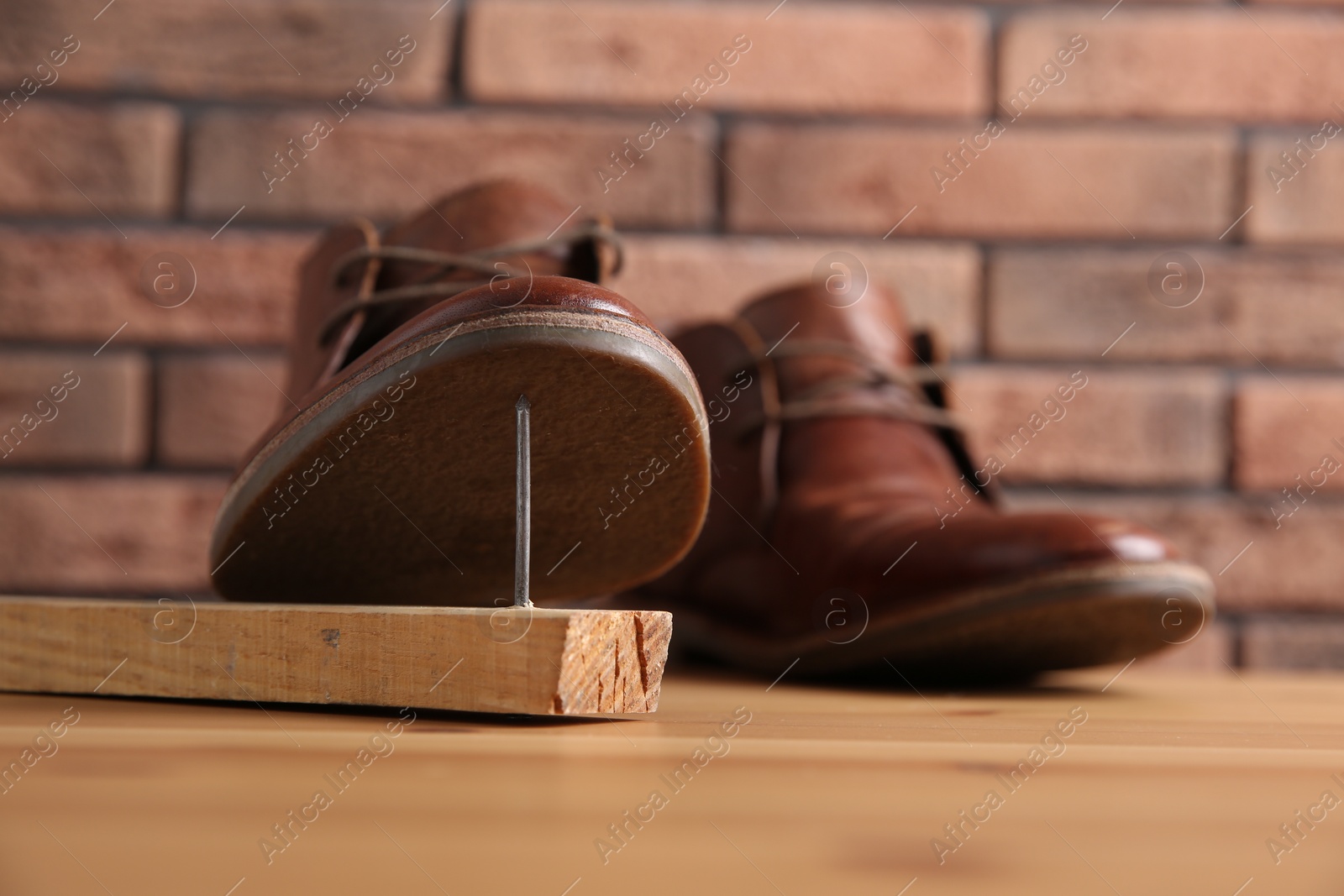 Photo of Metal nail in wooden plank and shoes on table