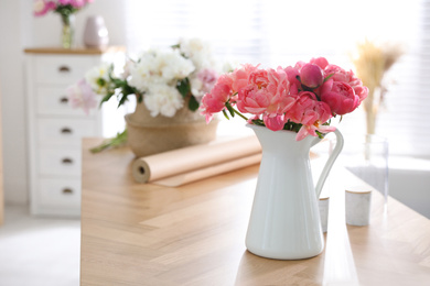 Photo of Beautiful bouquet of fragrant peonies in vase on table indoors