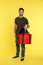 Young courier with thermo bag on color background. Food delivery service