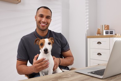 Photo of Young man with Jack Russell Terrier at desk in home office