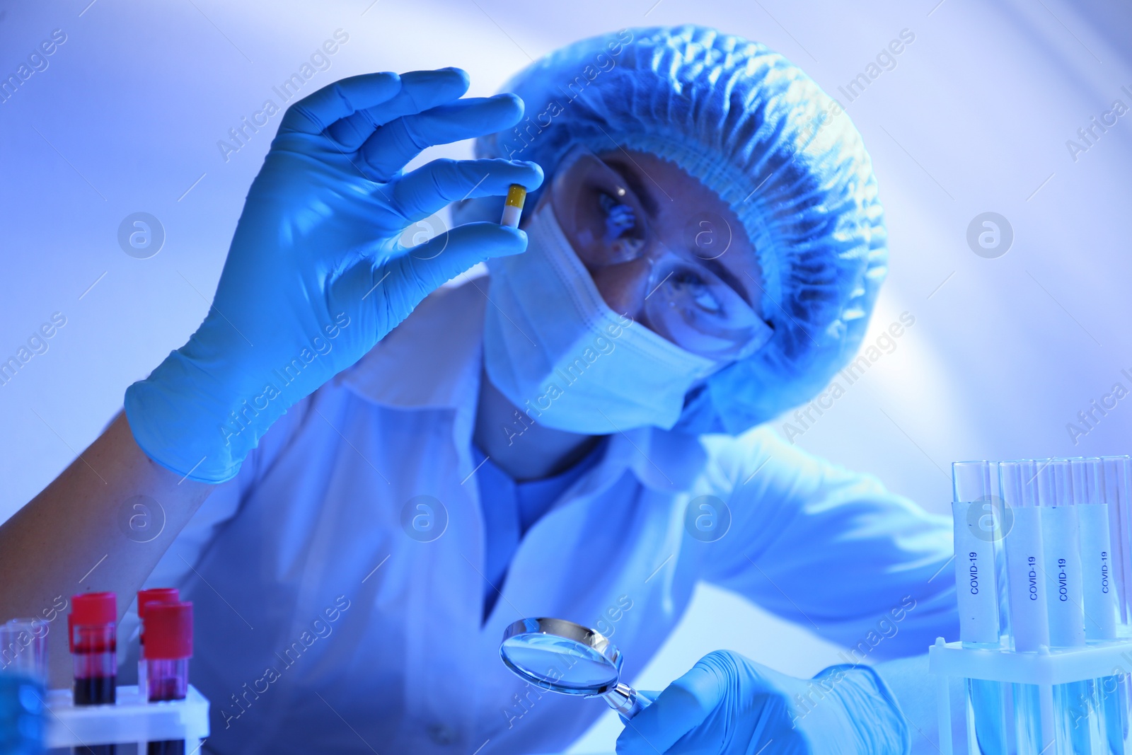 Photo of Scientist examining pill at table in laboratory