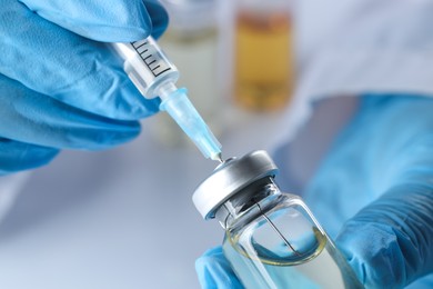 Doctor filling syringe with medication from glass vial, closeup