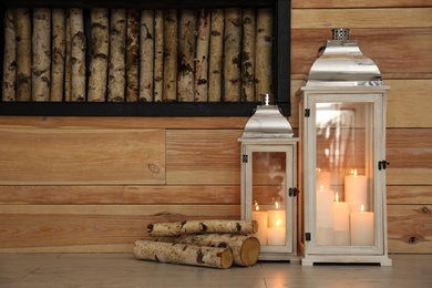 Photo of Decorative lanterns with candles on floor indoors, space for text. Interior elements