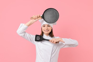Photo of Professional chef with frying pan and spatula having fun on pink background