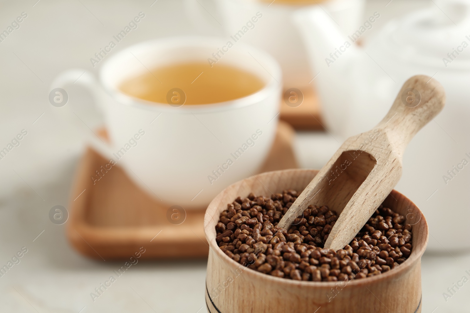 Photo of Bowl with buckwheat tea granules and wooden scoop on table, closeup. Space for text