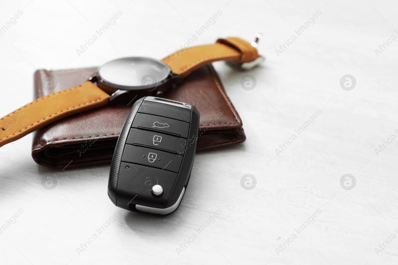 Photo of Wristwatch, remote car key and wallet on light background. Space for text