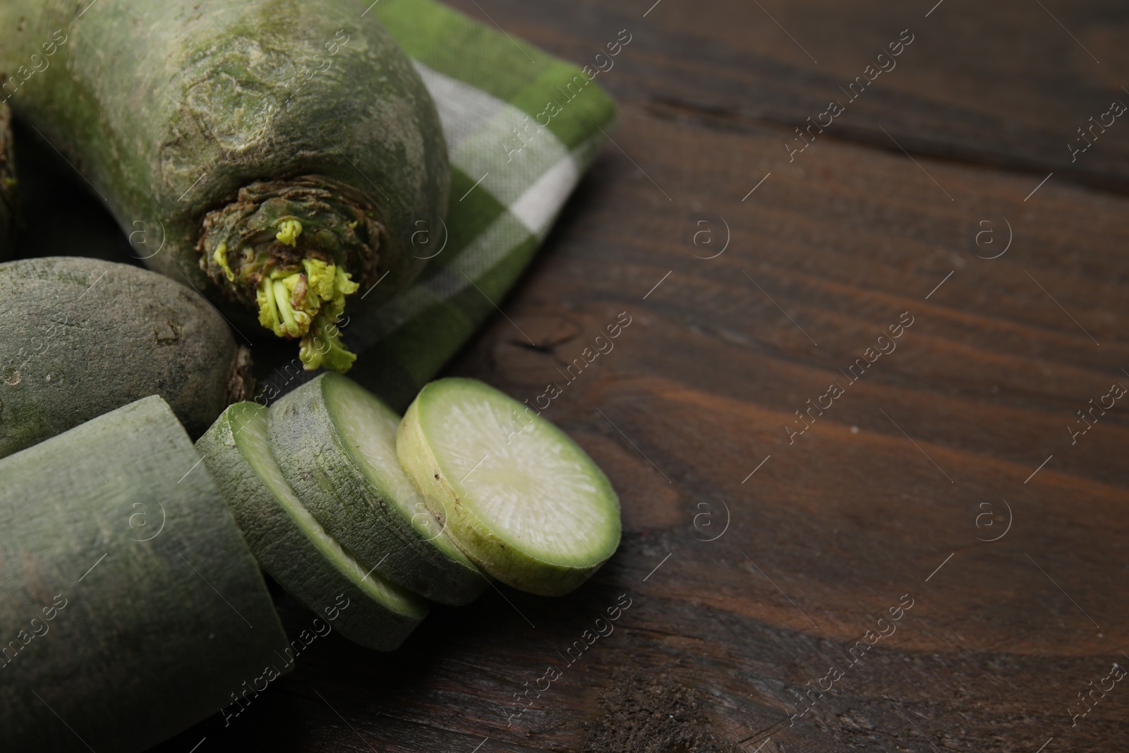 Photo of Green daikon radishes on wooden table, closeup. Space for text