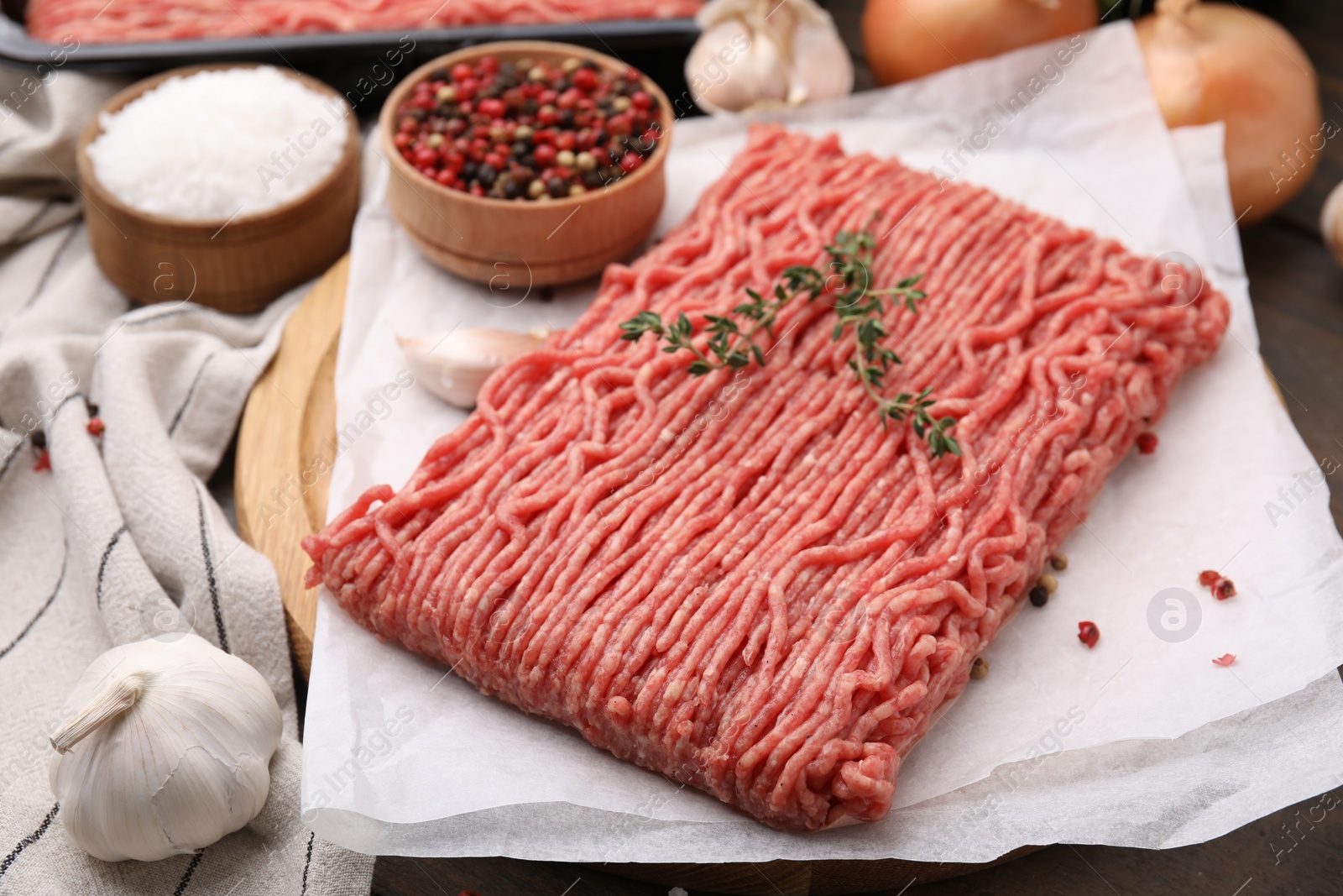 Photo of Fresh raw ground meat, thyme and peppercorns on table, closeup