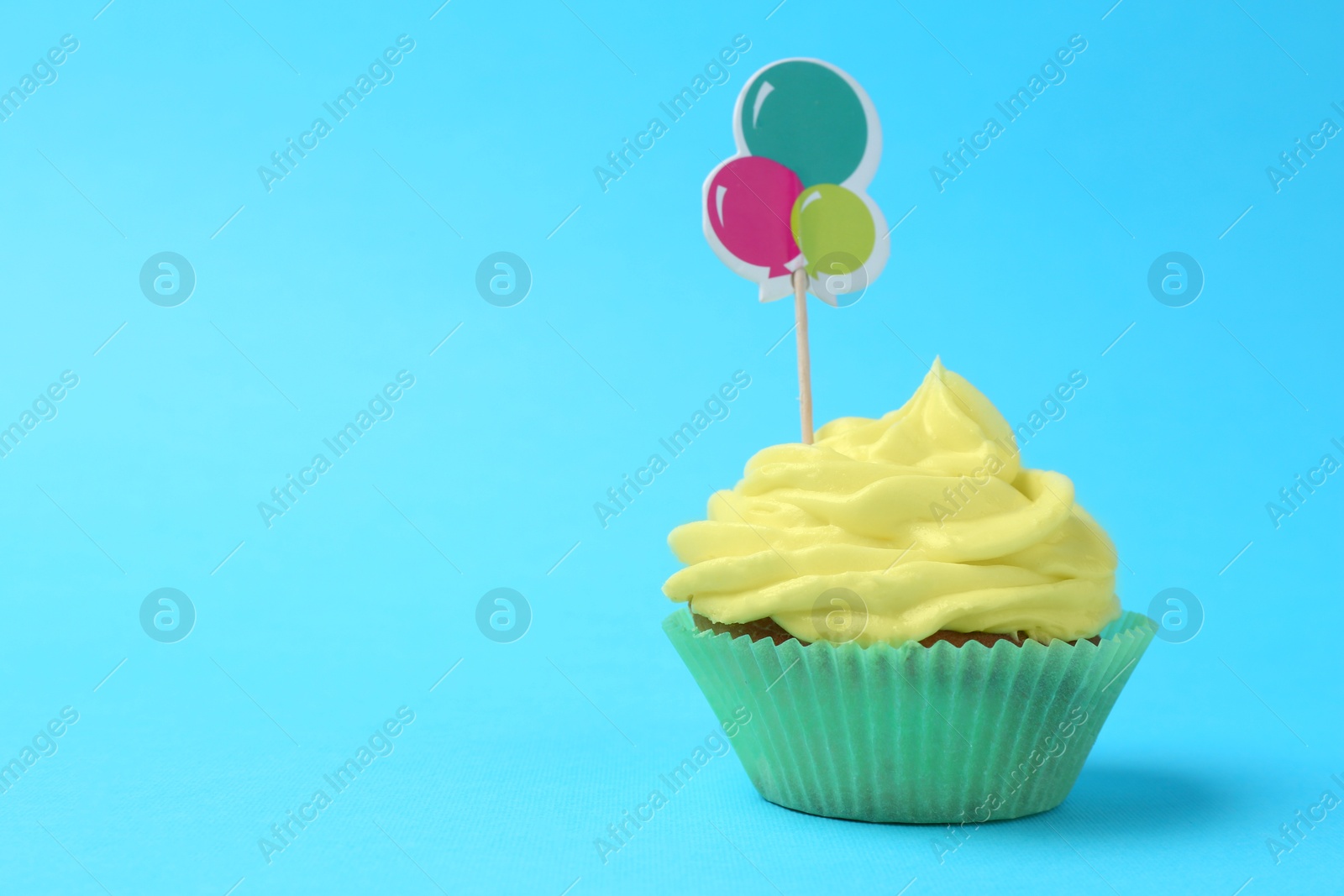 Photo of Delicious cupcake with bright cream and topper on light blue background. Space for text