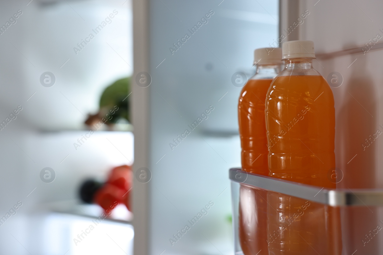 Photo of Open refrigerator with bottles of drink indoors, space for text