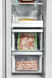 Drawers with frozen meat in modern refrigerator