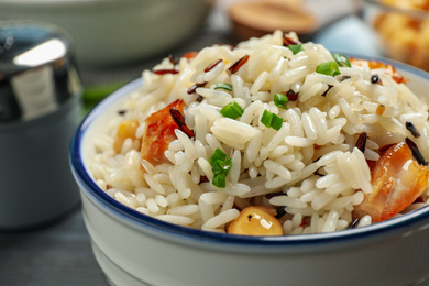 Photo of Delicious rice pilaf with chicken in bowl, closeup