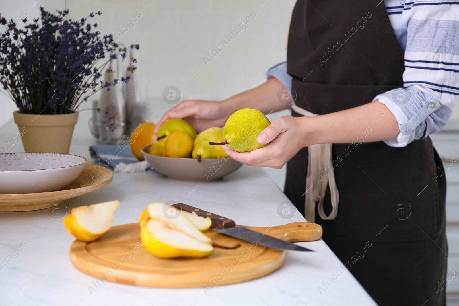 Photo of Woman holding fresh ripe pear in kitchen, closeup
