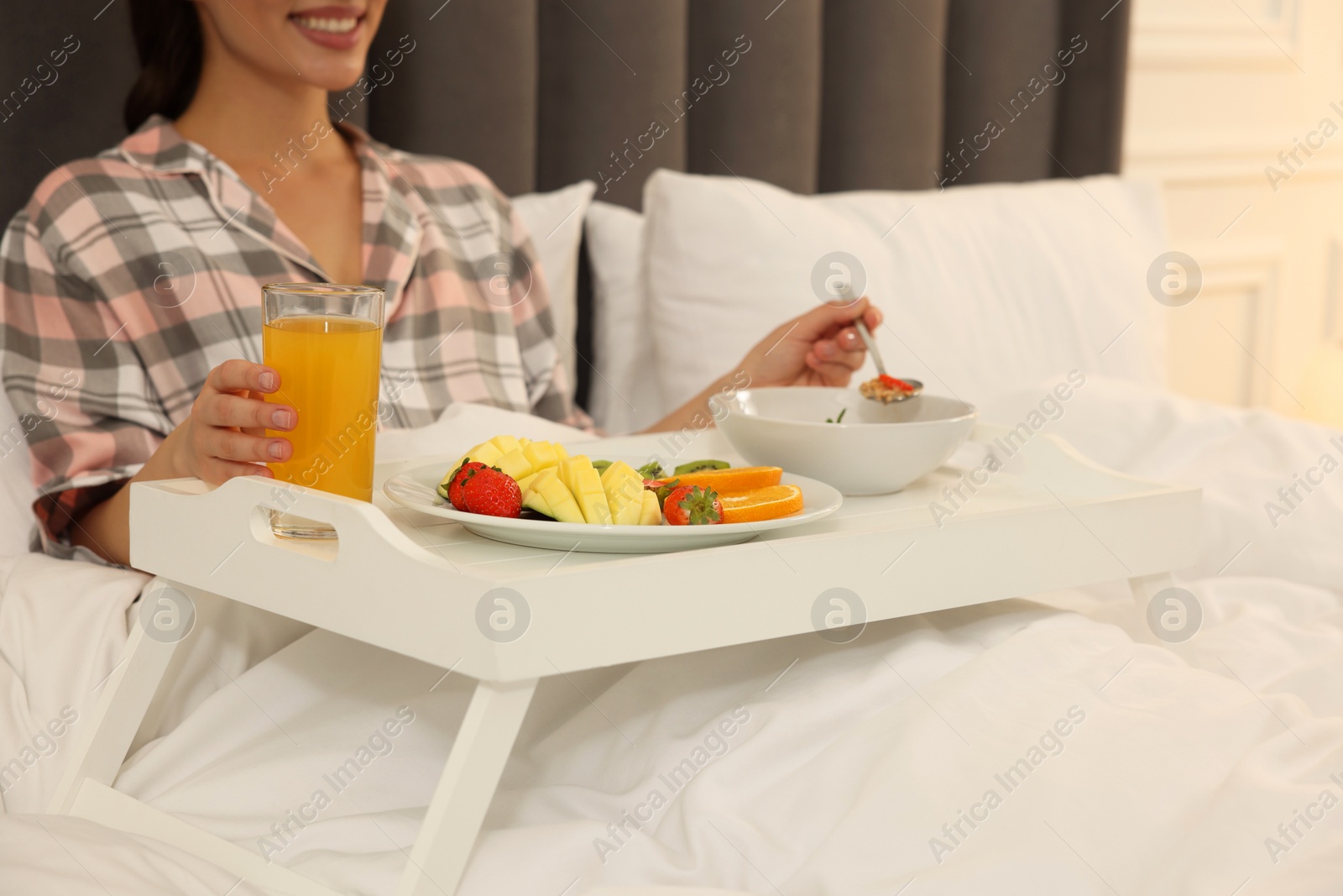 Photo of Young woman having breakfast on bed at home, closeup