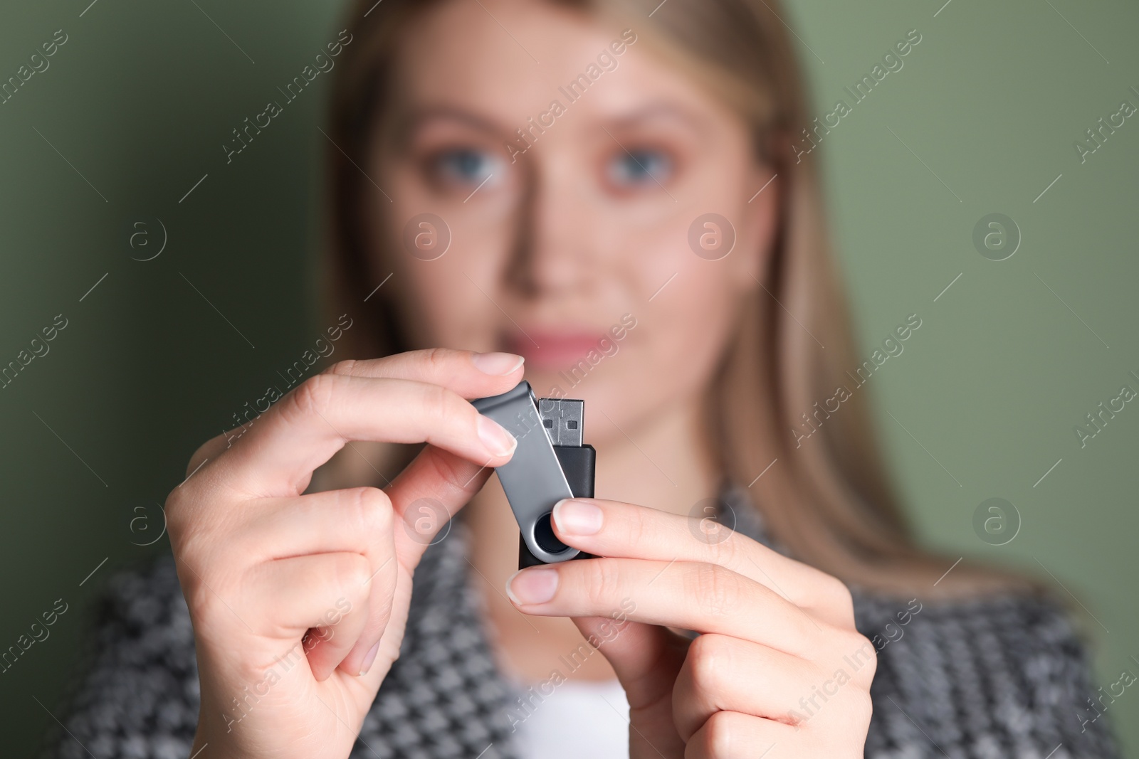 Photo of Woman holding usb flash drive against green background, focus on hands