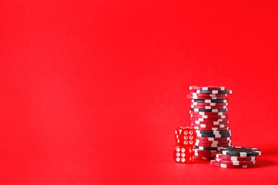 Photo of Poker chips and dices on red background, space for text
