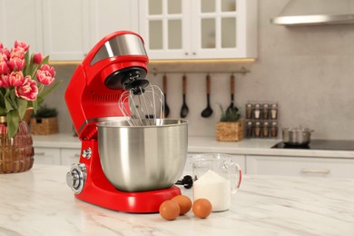 Photo of Modern red stand mixer, eggs and container with flour on white marble table in kitchen