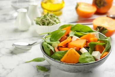 Photo of Delicious persimmon salad served on white marble table, closeup