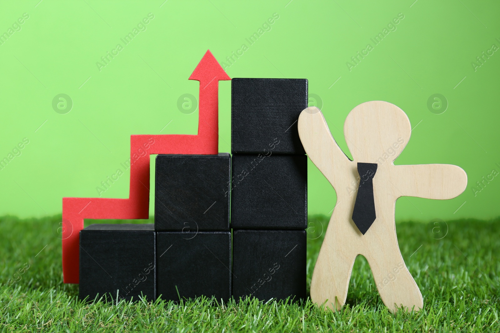 Photo of Stairs made of wooden cubes, human figure and up arrow against green background. Profit concept