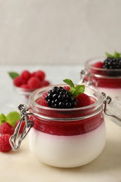 Photo of Delicious panna cotta with fruit coulis and fresh berries on light table
