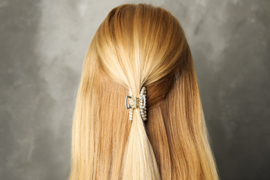 Young woman with beautiful hair claw on grey background, back view