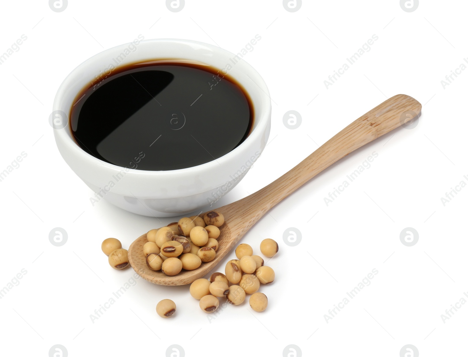 Photo of Tasty soy sauce in bowl, soybeans and spoon isolated on white