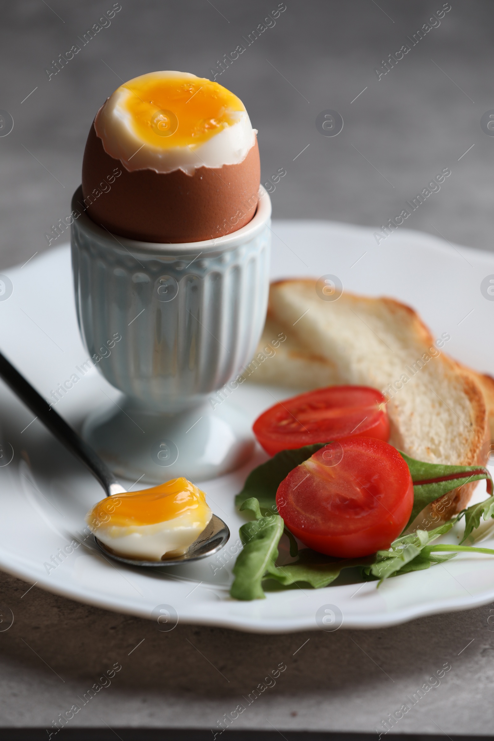 Photo of Delicious breakfast with soft boiled egg and fresh tomato served on grey table, closeup