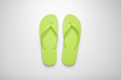 Photo of Light green flip flops on white background, top view