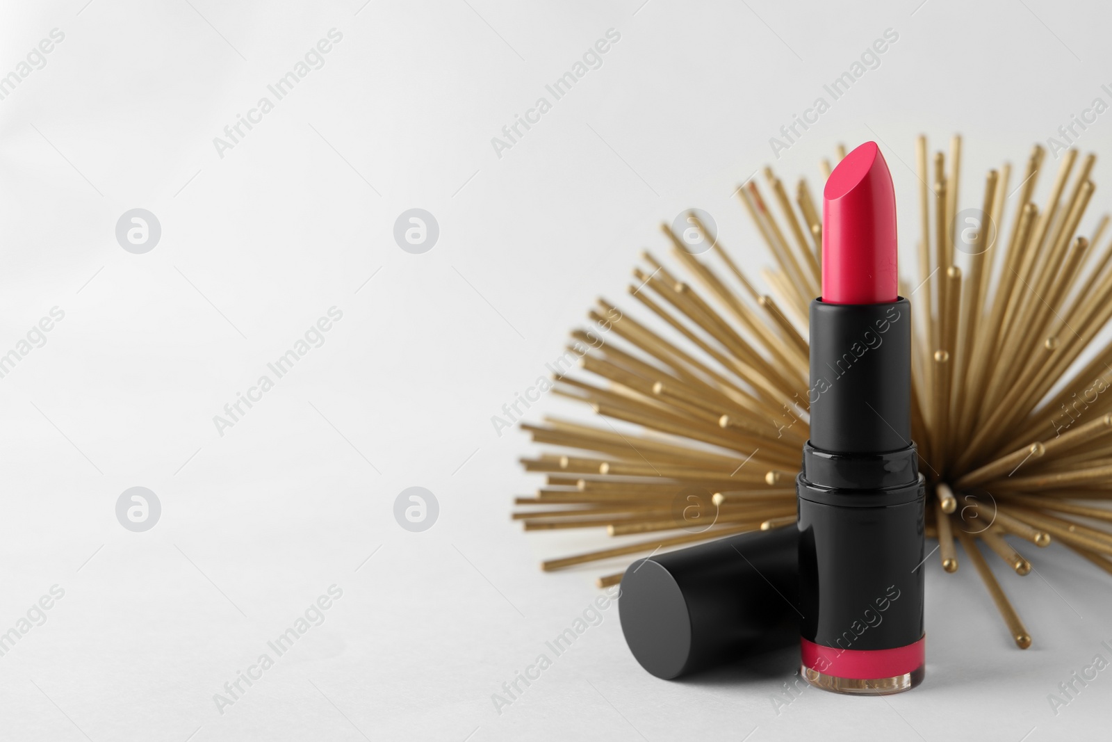 Photo of Beautiful pink lipstick and golden decoration on white background, space for text