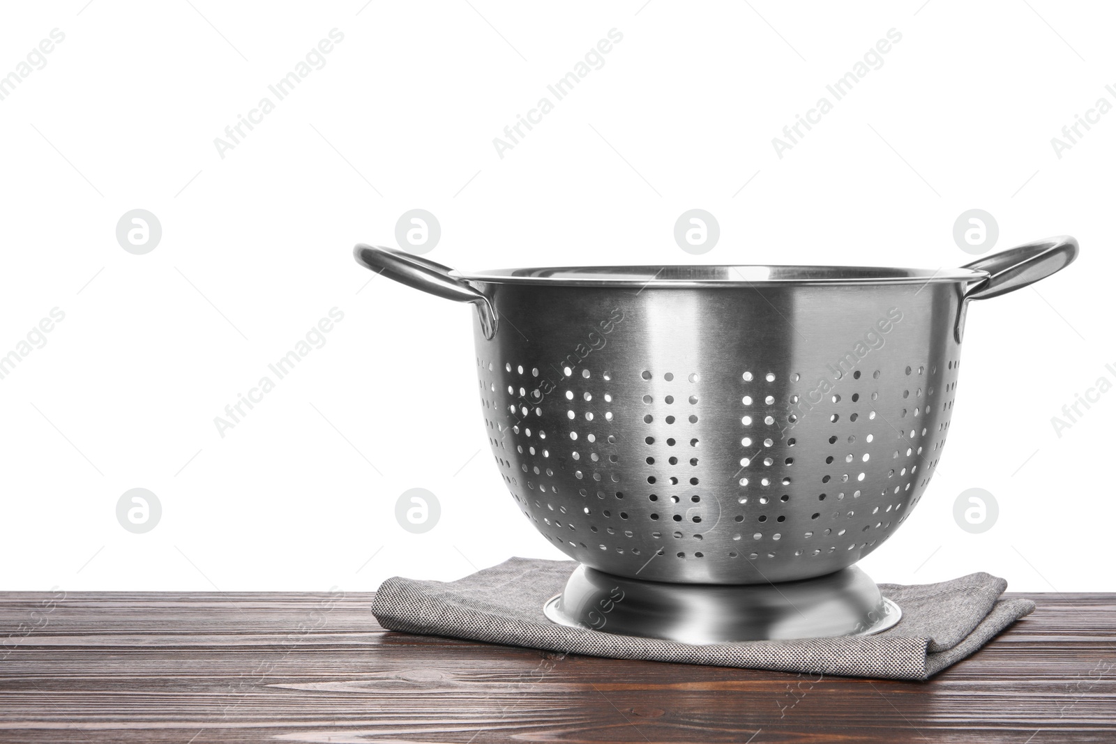 Photo of Metal colander and napkin on wooden table against white background. Space for text