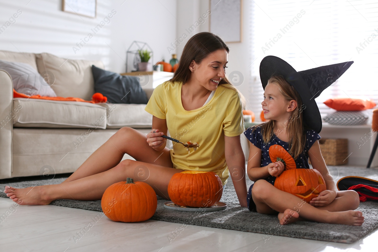 Photo of Mother and daughter making pumpkin jack o'lanterns at home. Halloween celebration