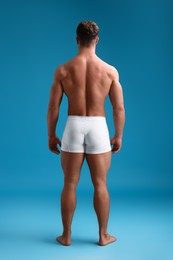 Muscular man on light blue background, back view. Sexy body