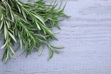 Photo of Sprigs of fresh rosemary on wooden table, above view. Space for text