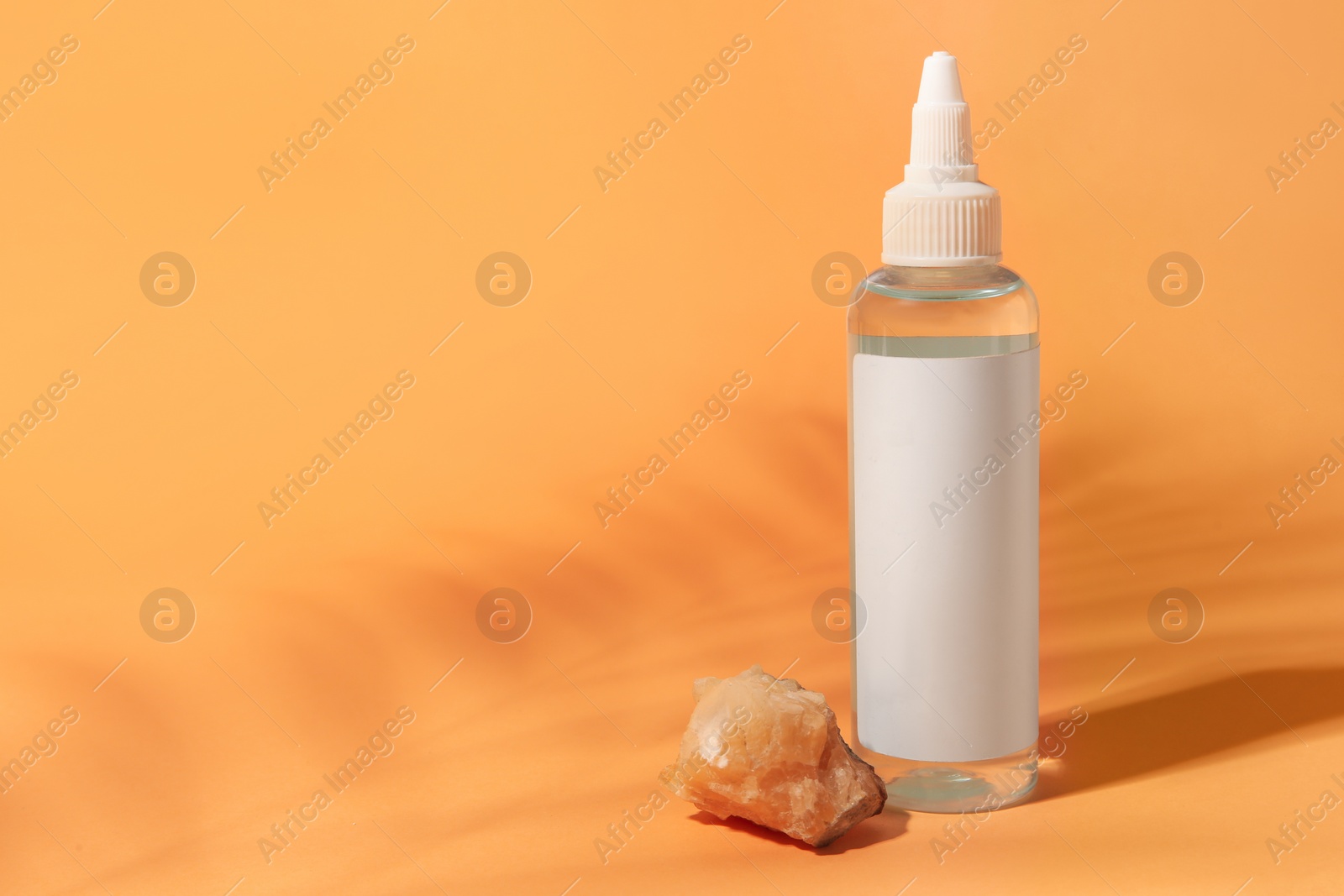 Photo of Cosmetic product and quartz gemstone on orange background, space for text