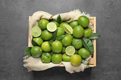 Photo of Crate with fresh ripe limes on gray background, top view