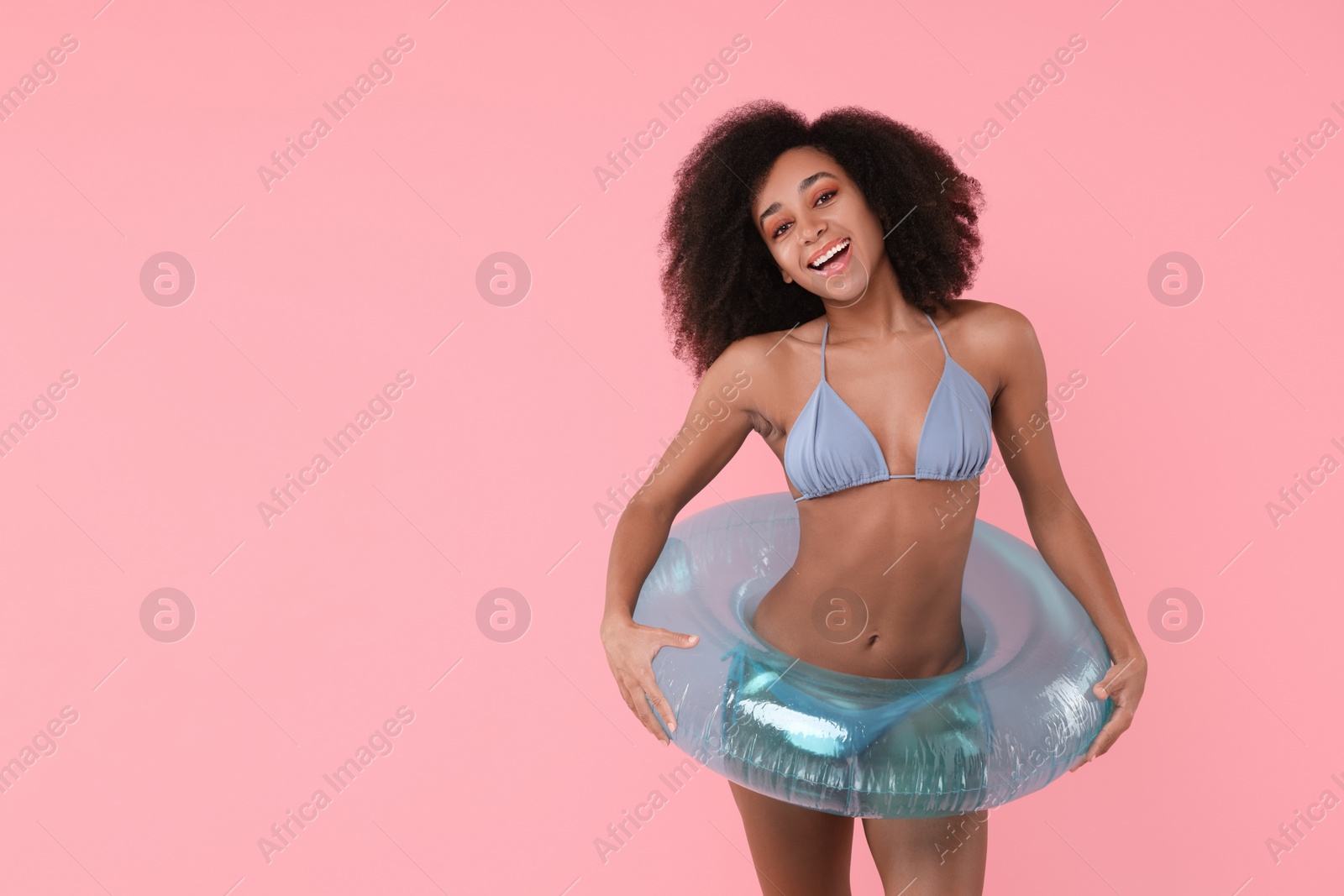 Photo of Beautiful woman in stylish bikini with inflatable ring on pink background, space for text