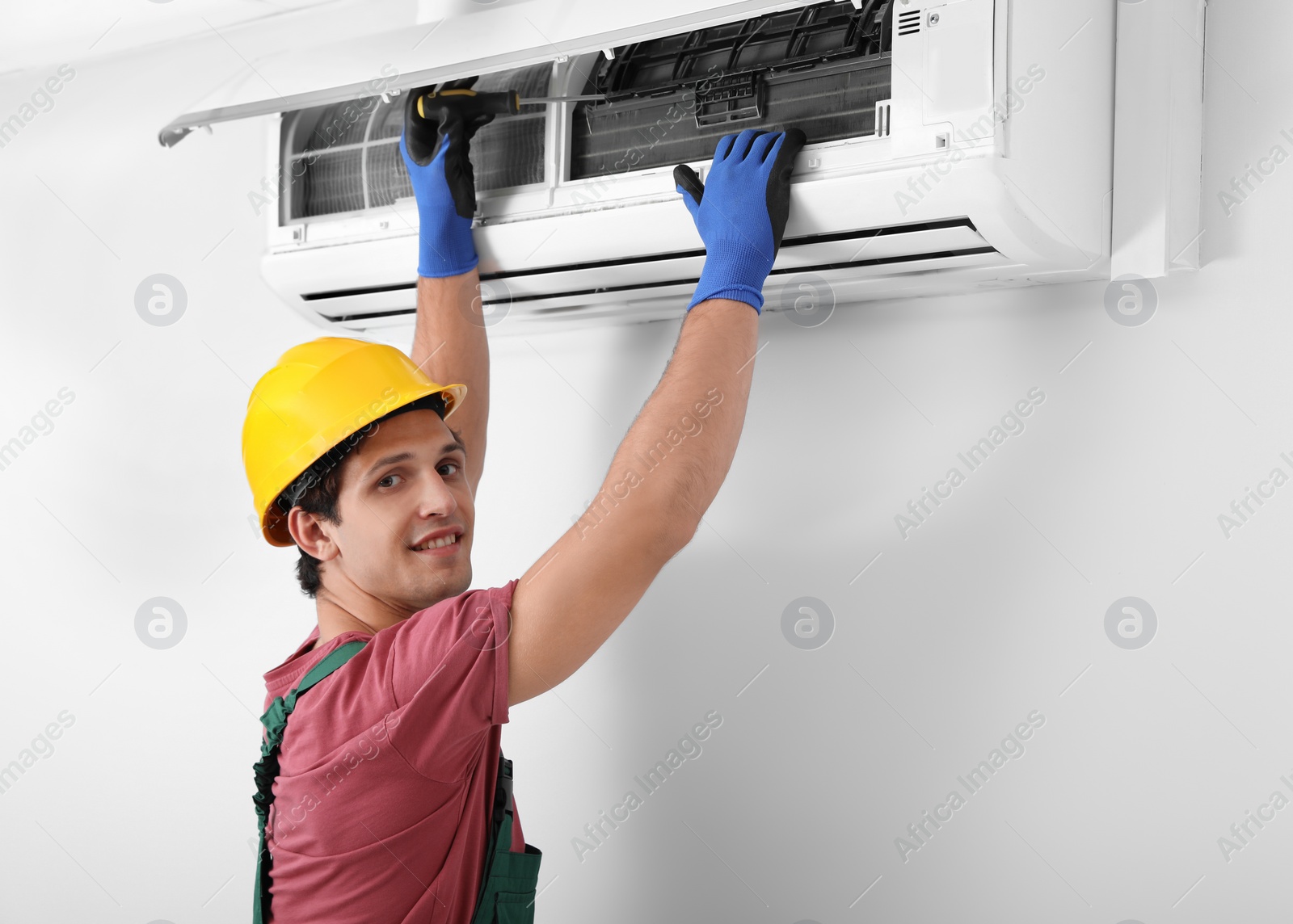 Photo of Male technician checking and repairing air conditioner indoors