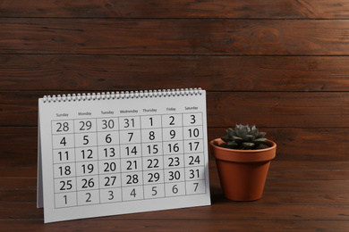 Photo of Paper calendar and succulent on wooden table