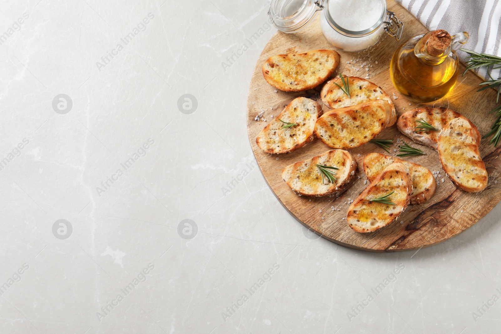 Photo of Tasty bruschettas with oil and rosemary on light grey marble table, top view. Space for text