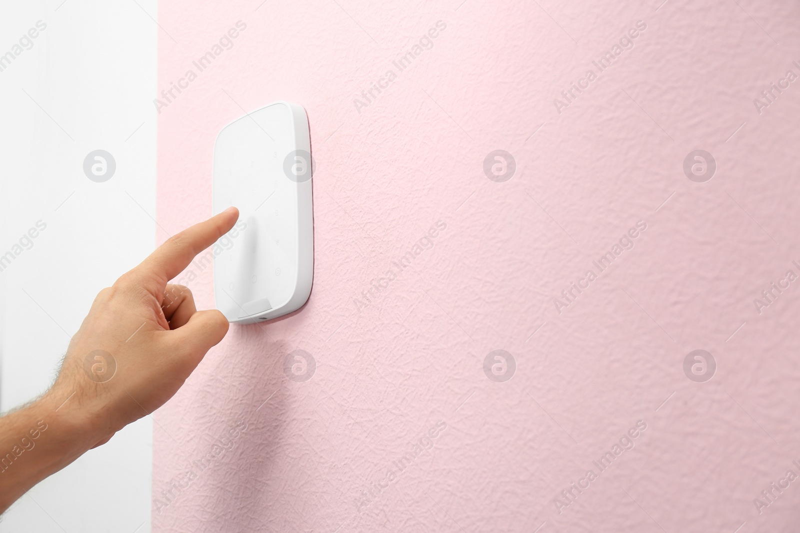 Image of Young man entering code on alarm system keypad indoors, closeup