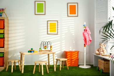 Stylish playroom interior with wooden table and stools