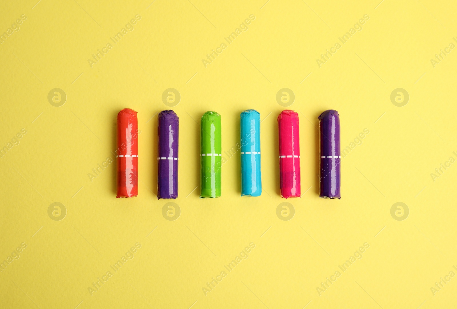 Photo of Colorful tampons on yellow background, flat lay