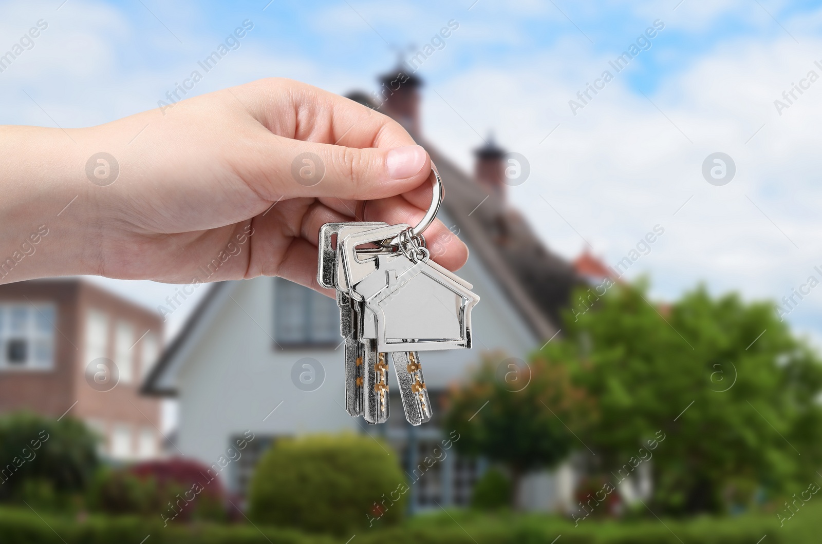 Image of Woman holding keys near house outdoors, closeup