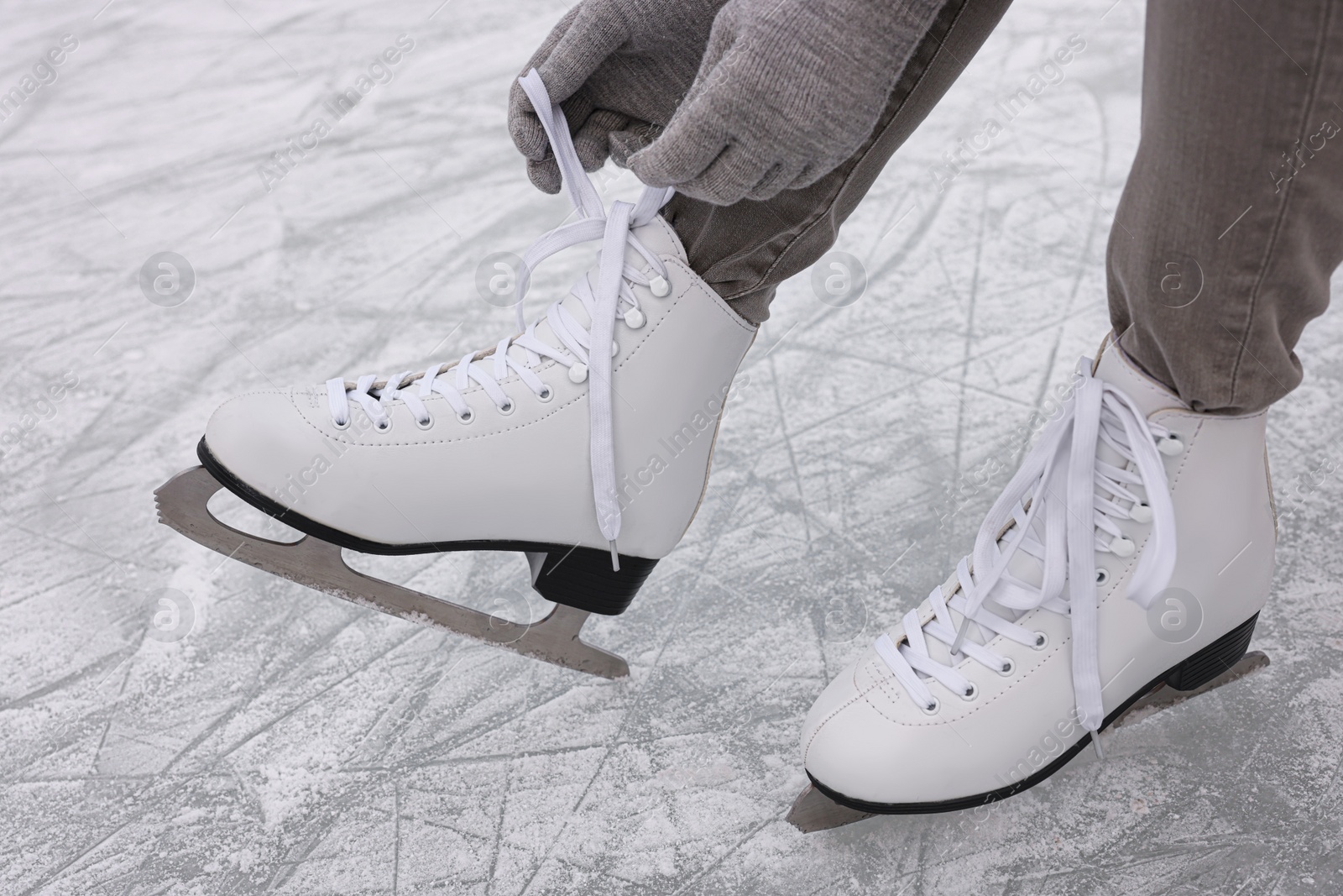 Photo of Woman lacing figure skates on ice, closeup